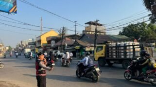 Personel Samapta Polresta Gowa mengatur lalu lintas pagi di Somba Opu, membantu warga menyeberang dan pengguna jalan demi kelancaran aktivitas masyarakat.